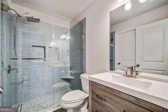 bathroom featuring vanity, a shower with shower door, and toilet