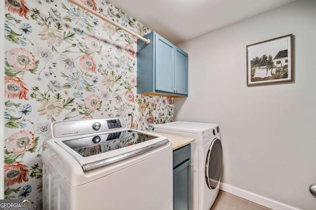 clothes washing area with cabinets and washing machine and dryer