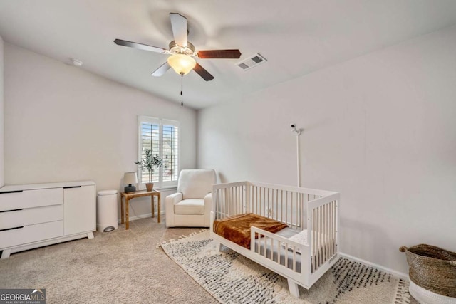 bedroom featuring a crib, carpet flooring, and ceiling fan