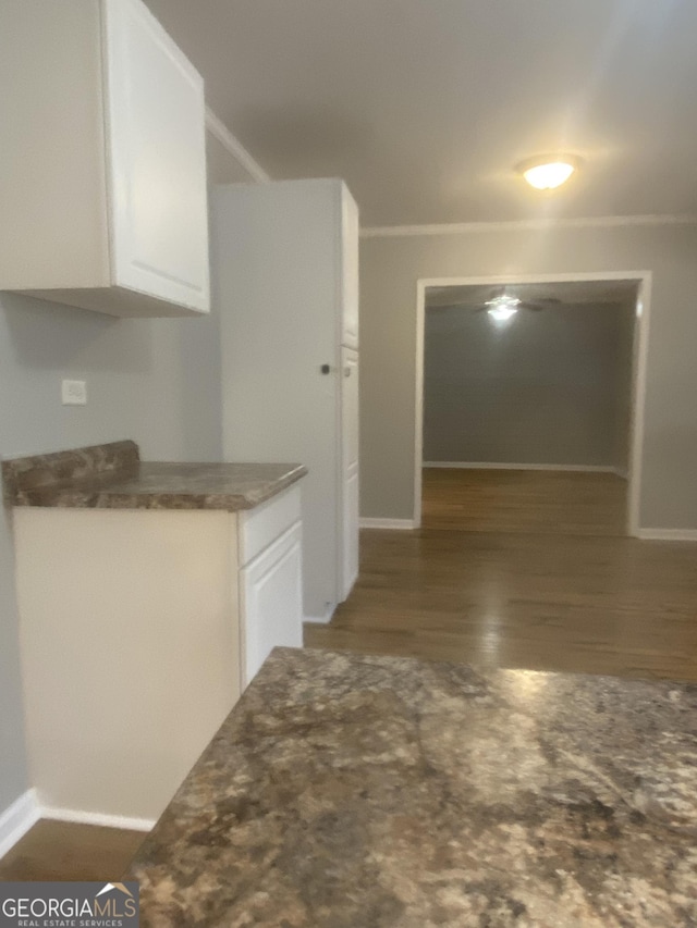 kitchen with white cabinetry, crown molding, and dark hardwood / wood-style flooring