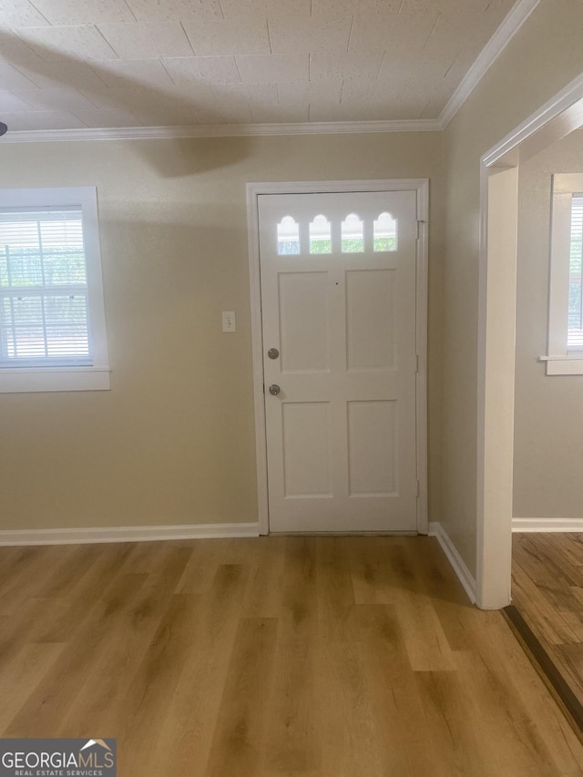 entryway with ornamental molding and light wood-type flooring