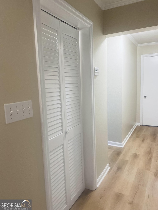 hallway featuring ornamental molding and light hardwood / wood-style floors