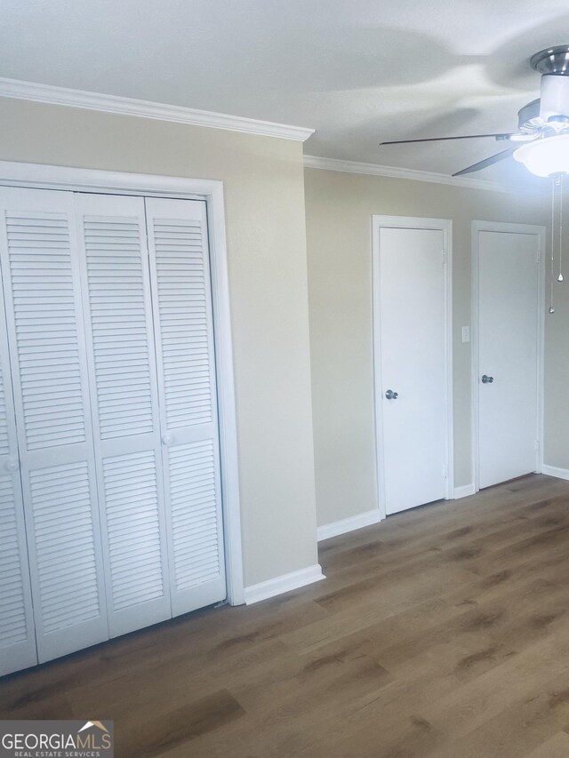 unfurnished bedroom featuring crown molding, dark hardwood / wood-style floors, ceiling fan, and a closet