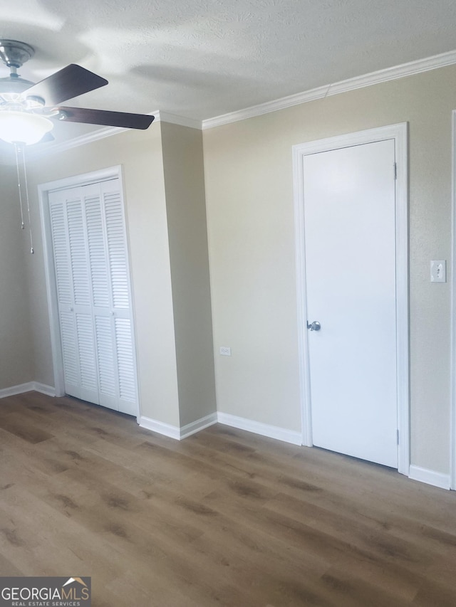 unfurnished bedroom with hardwood / wood-style floors, ornamental molding, ceiling fan, a textured ceiling, and a closet