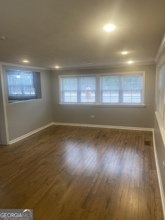 spare room with crown molding, a healthy amount of sunlight, and dark hardwood / wood-style flooring