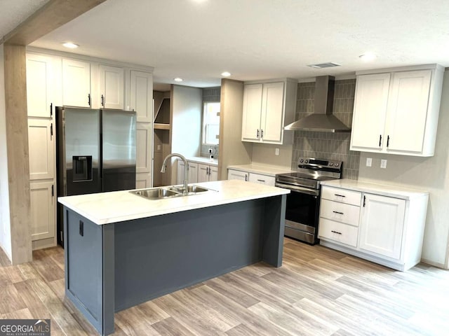 kitchen featuring an island with sink, sink, light hardwood / wood-style floors, stainless steel appliances, and wall chimney exhaust hood