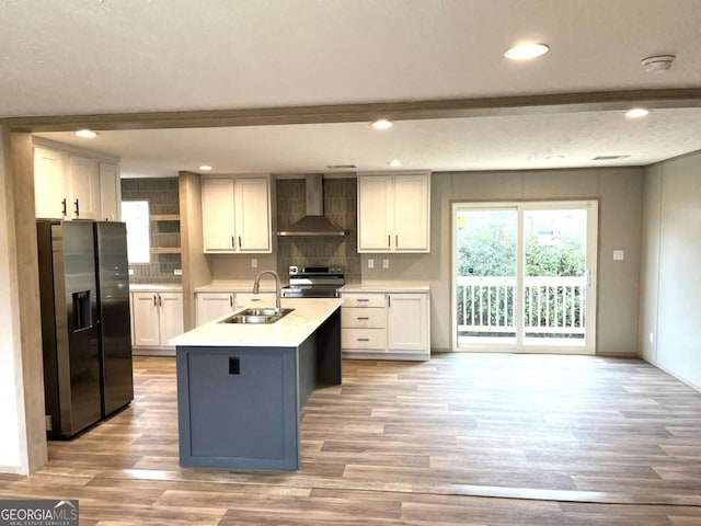 kitchen with appliances with stainless steel finishes, white cabinetry, sink, a kitchen island with sink, and wall chimney exhaust hood