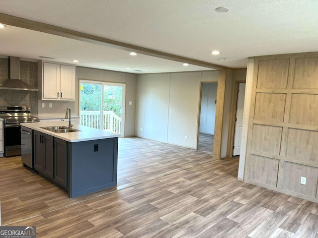 kitchen featuring appliances with stainless steel finishes, white cabinetry, sink, light hardwood / wood-style floors, and wall chimney range hood