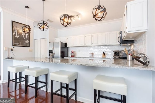 kitchen with stainless steel fridge with ice dispenser, hanging light fixtures, ornamental molding, and white cabinets