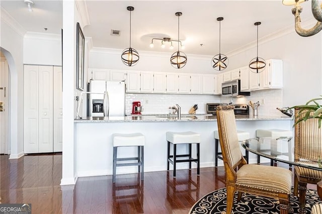 kitchen with light stone counters, stainless steel appliances, kitchen peninsula, and white cabinets