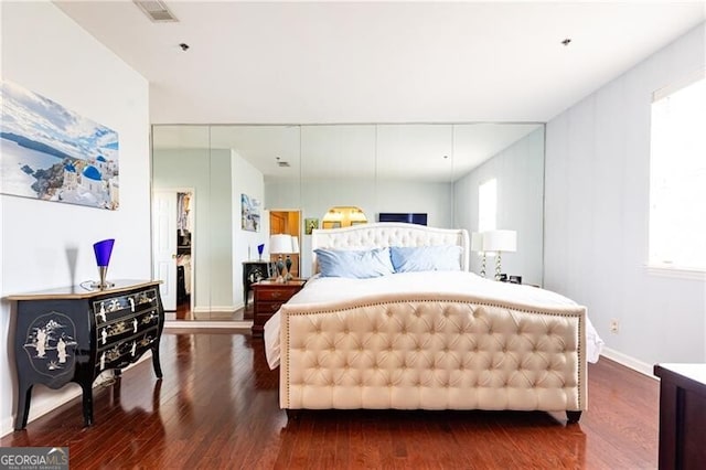 bedroom featuring multiple windows and dark hardwood / wood-style flooring