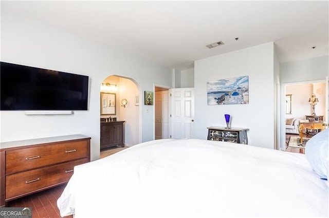 bedroom featuring dark hardwood / wood-style flooring and ensuite bath