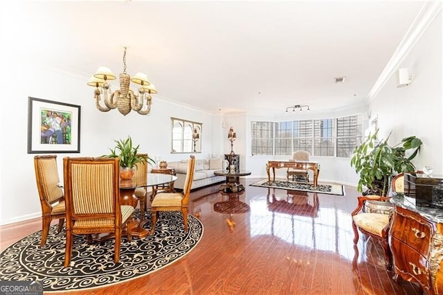 dining room with hardwood / wood-style flooring, crown molding, track lighting, and an inviting chandelier