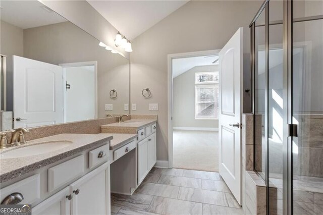 bathroom with vanity, a shower with shower door, and vaulted ceiling