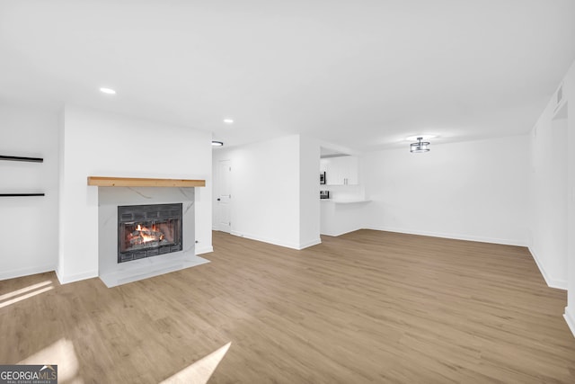 unfurnished living room featuring a premium fireplace and light hardwood / wood-style floors