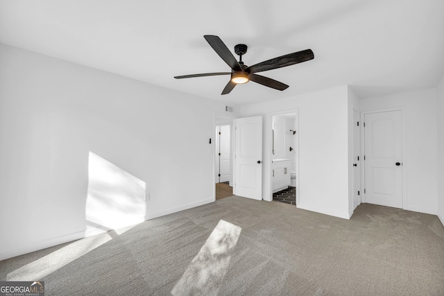 unfurnished bedroom with connected bathroom, dark carpet, and ceiling fan