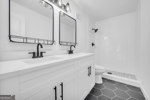 bathroom with tile patterned floors, toilet, vanity, and a tile shower