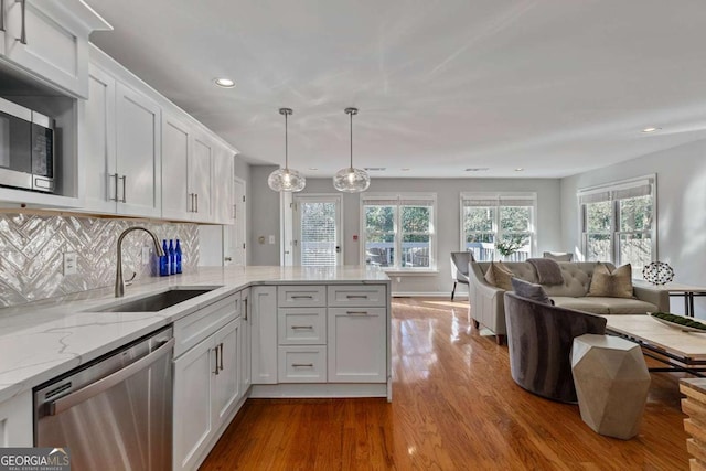 kitchen with sink, hanging light fixtures, a wealth of natural light, stainless steel appliances, and white cabinets