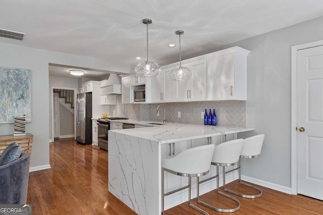 kitchen featuring sink, hanging light fixtures, kitchen peninsula, stainless steel appliances, and white cabinets