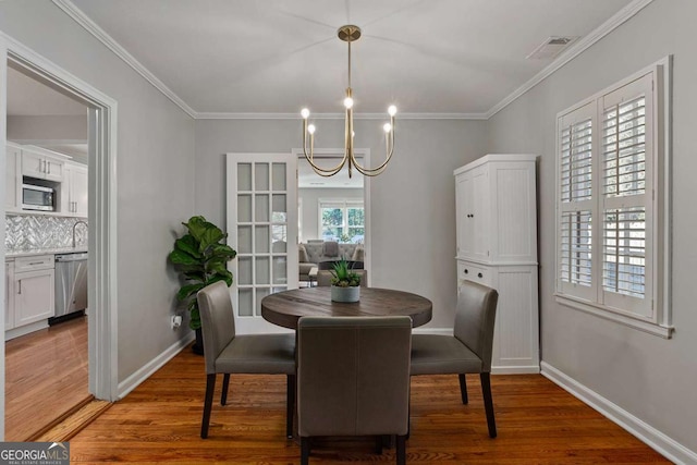 dining room featuring dark hardwood / wood-style flooring, crown molding, and an inviting chandelier