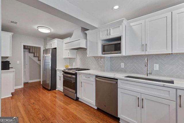 kitchen featuring stainless steel appliances, sink, custom exhaust hood, and white cabinets