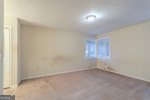 empty room featuring light carpet and a textured ceiling