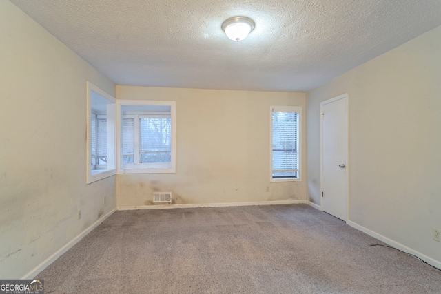 carpeted spare room featuring a textured ceiling