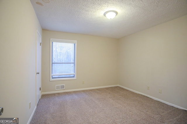 carpeted empty room featuring a textured ceiling