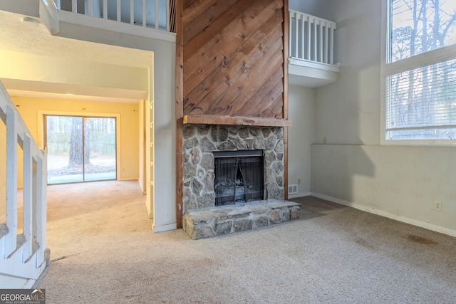 unfurnished living room featuring a fireplace, carpet flooring, and a high ceiling