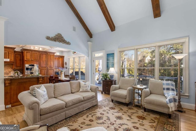 living room with beam ceiling, sink, high vaulted ceiling, and light hardwood / wood-style flooring