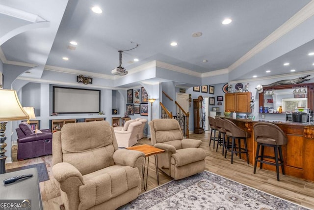 home theater room with indoor bar, ornamental molding, and light hardwood / wood-style floors