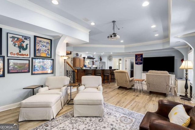 living room featuring crown molding, light wood-type flooring, and a tray ceiling