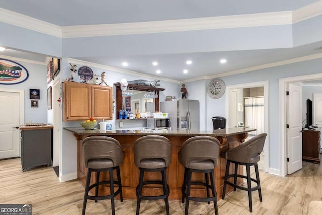 kitchen featuring stainless steel appliances, crown molding, a breakfast bar, and light hardwood / wood-style flooring