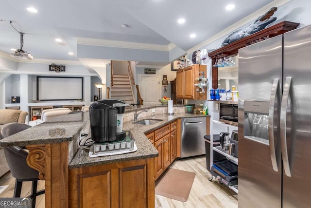 kitchen with ornamental molding, appliances with stainless steel finishes, a kitchen breakfast bar, and dark stone countertops