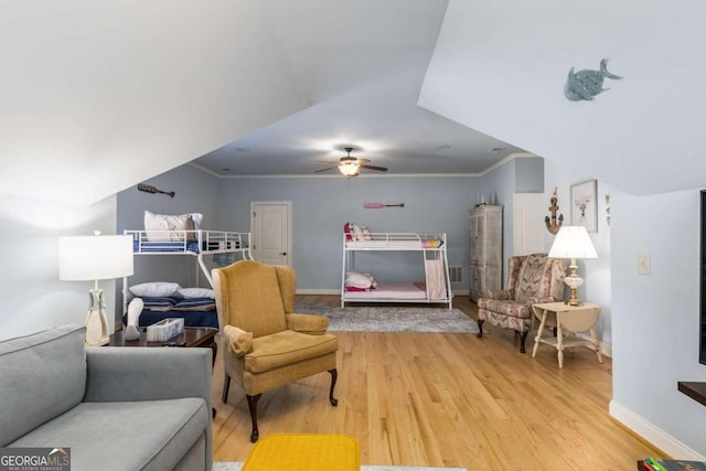 living area with ceiling fan, ornamental molding, and light wood-type flooring