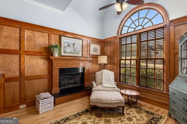 living area featuring vaulted ceiling, ceiling fan, a premium fireplace, and light hardwood / wood-style floors