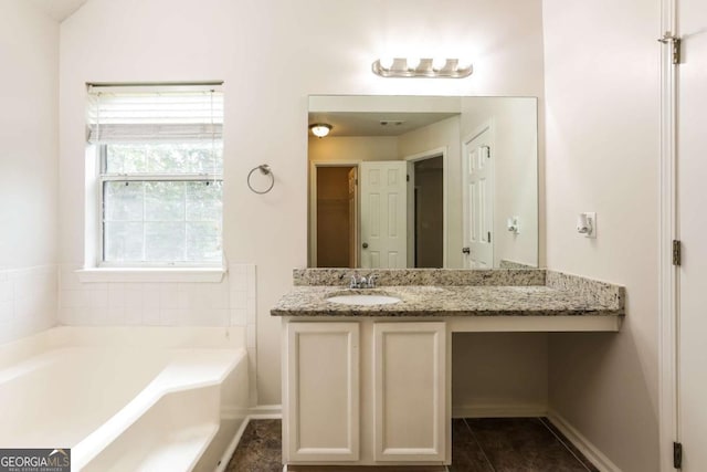 bathroom with a washtub, vanity, and tile patterned floors