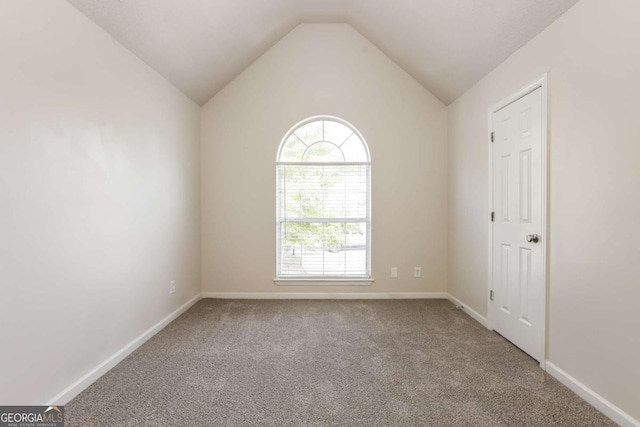 empty room featuring vaulted ceiling and carpet