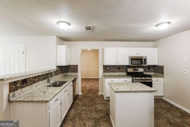 kitchen with white cabinetry, sink, stainless steel appliances, and light stone countertops