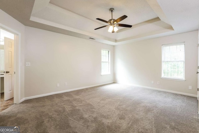 carpeted empty room with a textured ceiling, a raised ceiling, and ceiling fan