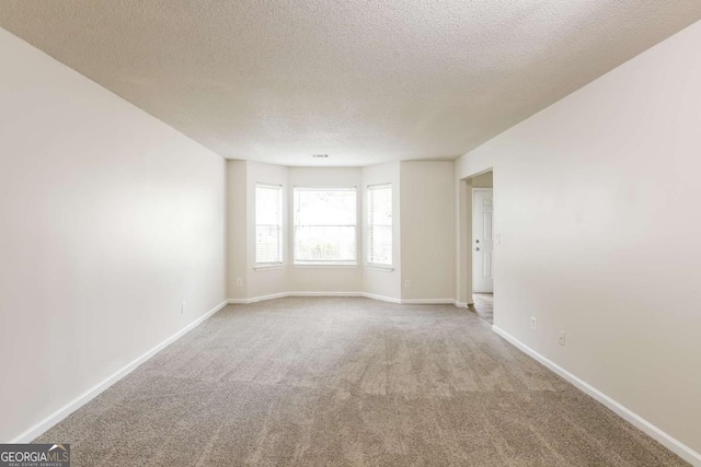 carpeted empty room featuring a textured ceiling