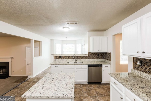 kitchen with sink, stainless steel dishwasher, white cabinets, and light stone counters