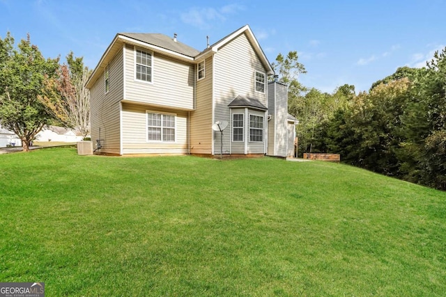 rear view of house with central air condition unit and a lawn