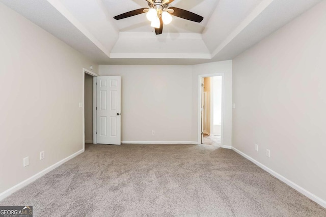 carpeted spare room featuring a tray ceiling and ceiling fan