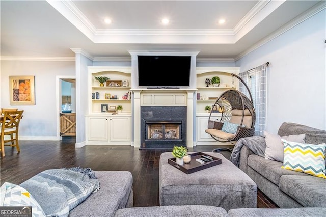 living room featuring crown molding, a tray ceiling, dark hardwood / wood-style floors, and a premium fireplace