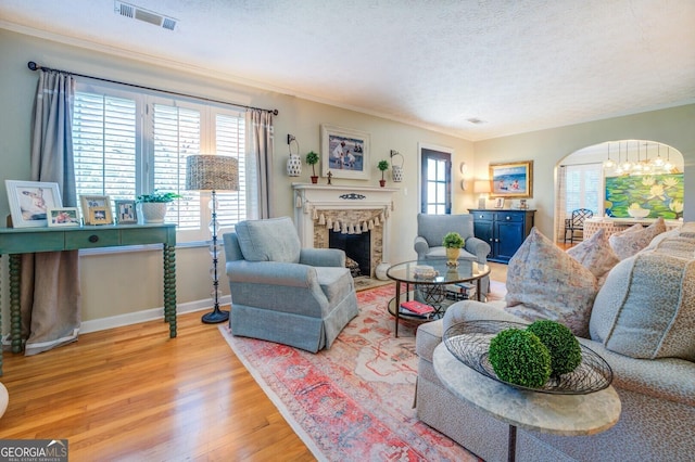 living room with crown molding, a notable chandelier, a textured ceiling, and light hardwood / wood-style flooring