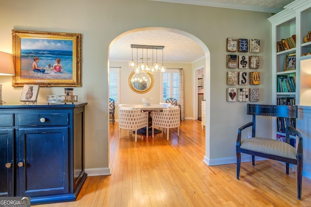 hall with crown molding, a textured ceiling, built in features, and light hardwood / wood-style floors