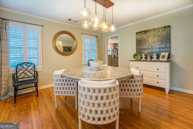 dining area featuring a notable chandelier, crown molding, and light wood-type flooring