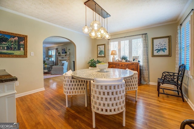 dining room featuring an inviting chandelier, wood-type flooring, ornamental molding, and a textured ceiling