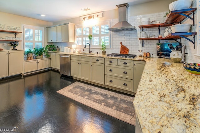 kitchen with wall chimney range hood, sink, appliances with stainless steel finishes, light stone counters, and tasteful backsplash